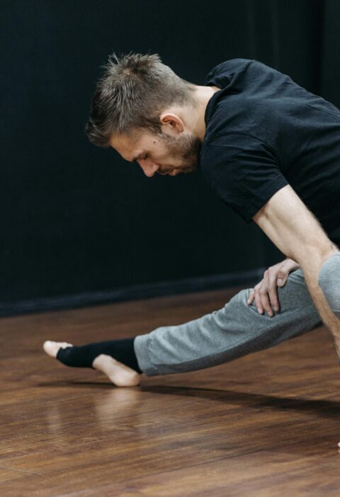 Mid-adult man stretching in a dance studio, emphasizing flexibility and balance.